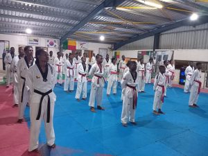 Taekwondo béninois : Le Gouvernement et la Fédération en action pour une professionnalisation durable Dans une dynamique de structuration et de montée en compétence, la Fédération béninoise de Taekwondo (FBTAE) poursuit activement la professionnalisation de la discipline au Bénin. Du vendredi 13 au dimanche 15 juin 2025, une session de formation intensive se tient au siège fédéral, à l’attention des responsables techniques des ligues régionales. Cette formation marque une étape décisive dans le processus de modernisation du taekwondo national, avec l’appui technique du Grand Maître Pierre Ogoudjobi, figure emblématique de la discipline. L’objectif est clair : renforcer les capacités techniques, pédagogiques, managériales et stratégiques des participants afin d’harmoniser les pratiques sur tout le territoire. Un pas décisif vers un Taekwondo moderne et compétitif Au-delà des aspects sportifs, cette initiative s’attaque aux véritables défis de la professionnalisation. Les responsables régionaux seront formés à : L’harmonisation des méthodes d’enseignement La maîtrise des nouvelles réglementations internationales (WT) Le perfectionnement en arbitrage La planification, le suivi et l’évaluation des performances sportives Cette formation intègre également des modules sur la gestion efficace des équipes, la communication et le leadership, des compétences devenues indispensables pour accompagner les athlètes béninois vers l’excellence et la compétitivité internationale. Un levier de cohésion nationale et de performance En structurant et professionnalisant les encadrements régionaux, la FBTAE entend également renforcer la cohésion entre les différents acteurs du Taekwondo au Bénin. La vision portée par le Grand Maître Pierre Ogoudjobi vise à fédérer les techniciens autour d’un Taekwondo rigoureux, inclusif et performant. Cette session de formation n’est pas une simple mise à niveau ; elle constitue une véritable stratégie de transformation durable, capable de hisser le Taekwondo béninois vers les standards internationaux et de faire rayonner le Bénin sur les podiums africains et mondiaux. Avec cette initiative, la Fédération béninoise de Taekwondo, en synergie avec les ambitions du gouvernement, jette les bases d’une nouvelle ère pour le sport béninois. Ablam AKODJEVO